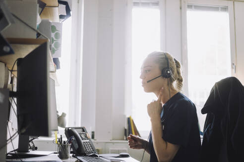 Female healthcare worker consulting on video call through computer at clinic - MASF37477