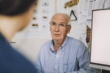 Senior male patient wearing eyeglasses and listening to nurse during visit in clinic - MASF37524