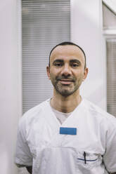 Porträt eines lächelnden reifen männlichen Arztes mit Laborkittel im Krankenhaus - MASF37568