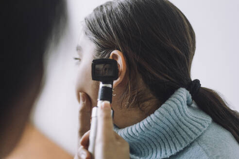 Doctor examining patient's ear using Otoscope at hospital - MASF37572