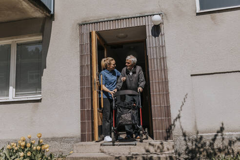 Weibliche Pflegekraft unterstützt älteren Mann beim Auszug mit Gehhilfe - MASF37616
