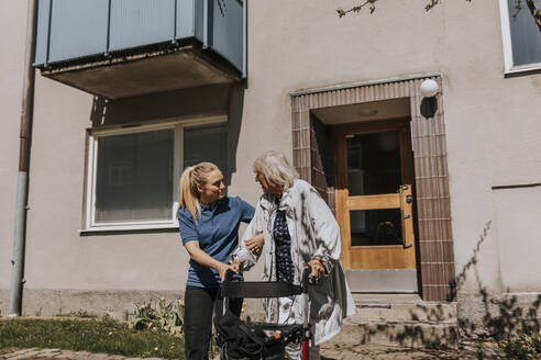 Weibliche Pflegekraft unterstützt ältere Frau beim Auszug mit Gehhilfe - MASF37618