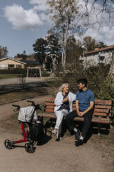 Ältere Frau im Gespräch mit männlichem Betreuer, während sie auf einer Bank sitzt - MASF37632
