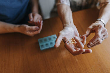 High angle view of senior woman with vitamins in hand at home - MASF37664