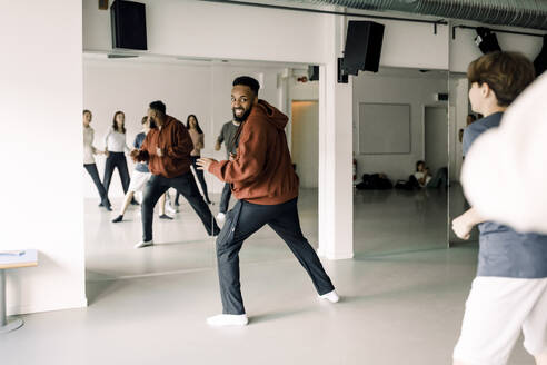 Lächelnder Lehrer, der seine Schüler beim Tanzen im Studio der High School beobachtet - MASF37749