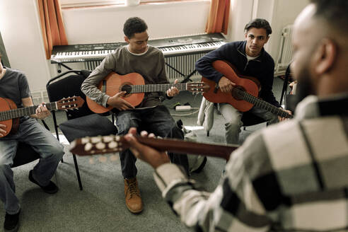 Männliche Teenager lehnen Gitarre im Musikunterricht an der High School - MASF37754