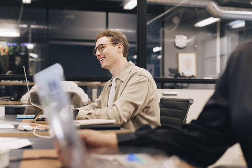 Happy businessman wearing eyeglasses sitting at desk working in office - MASF37801