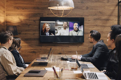 Multiracial colleagues planning strategy through video conference in board room - MASF37829