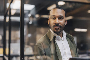 Thoughtful businessman standing in illuminated office - MASF37850