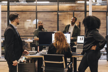 Colleagues and manager discussing over computer in office - MASF37858