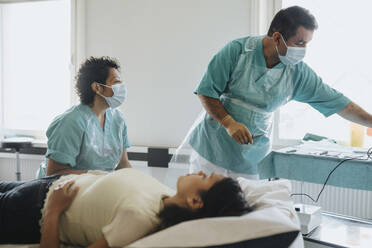 Surgeons in masks examining female patient in hospital - MASF37904