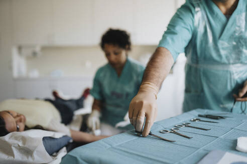 Male surgeon arranging surgical equipment on table in hospital - MASF37908