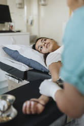 Young woman lying on examination table while surgeon operating in hospital - MASF37913