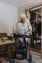 Senior woman walking at home using mobility walker - MASF37951