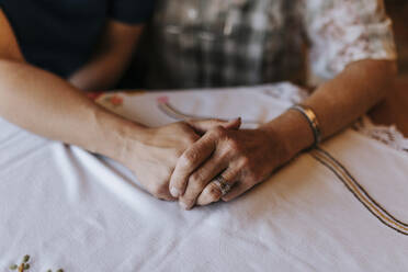 Weibliche Pflegekraft hält faltige Hand einer älteren Frau zu Hause - MASF37982