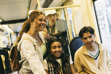 Happy male and female friends enjoying while traveling in train - MASF38047