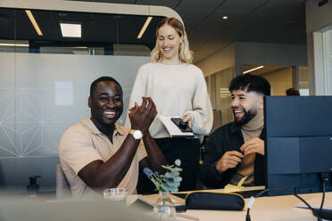 Happy businessman applauding with colleagues in coworking office - MASF38082