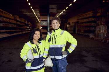 Porträt einer lächelnden multirassischen Mitarbeiterin in Arbeitskleidung, die in einer Fabrik steht - MASF38194