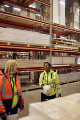 Happy multiracial female coworkers standing in distribution warehouse - MASF38195