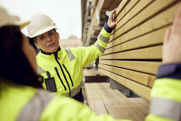 Multiracial female workers discussing over planks stacked at industry - MASF38265