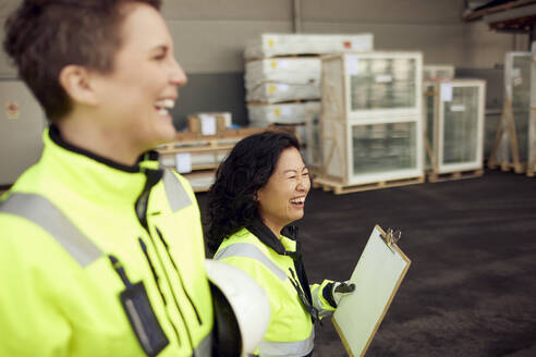 Happy multiracial female colleagues walking in distribution warehouse - MASF38275