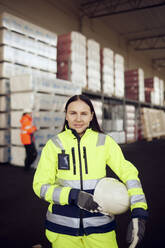 Portrait of smiling female blue-collar worker in protective workwear at industry - MASF38283