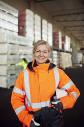 Portrait of smiling female blue-collar worker in protective workwear at factory - MASF38285
