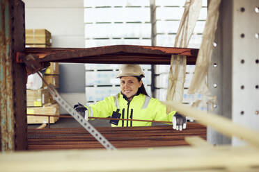 Porträt einer lächelnden Arbeiterin in Arbeitsschutzkleidung bei der Arbeit in der Industrie - MASF38289