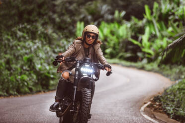 Beautiful female biker driving a cafe' racer motorbike - Pretty girl driving a motorbike and enjoying the roadtrip - DMDF03203