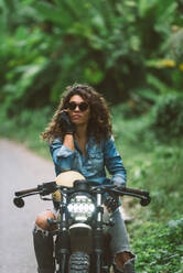 Beautiful female biker driving a cafe' racer motorbike - Pretty girl driving a motorbike and enjoying the roadtrip - DMDF03205