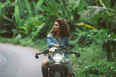 Schöne Bikerin auf einem Cafe'-Racer-Motorrad - Hübsches Mädchen fährt Motorrad und genießt den Roadtrip - DMDF03206