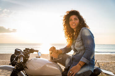 Schöne Bikerin auf einem Cafe'-Racer-Motorrad - Hübsches Mädchen fährt Motorrad und genießt den Roadtrip - DMDF03210