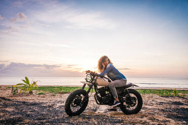 Beautiful female biker driving a cafe' racer motorbike - Pretty girl driving a motorbike and enjoying the roadtrip - DMDF03214