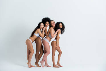Multi-ethnic group of beautiful women posing in underwear in a beauty  studio - Multicultural fashion models showing their beautiful bodies as  they are, concepts about beauty, acceptance and diversity stock photo