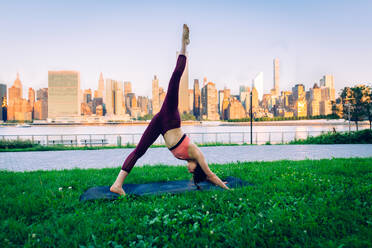 Beautiful sportive woman doing yoga meditation in a park - Girl relaxing with serene expression outdoors - DMDF03284