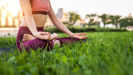 Beautiful sportive woman doing yoga meditation in a park - Girl relaxing with serene expression outdoors - DMDF03285