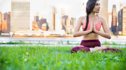 Beautiful sportive woman doing yoga meditation in a park - Girl relaxing with serene expression outdoors - DMDF03287