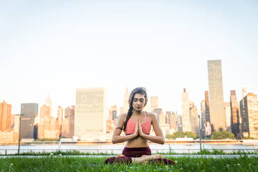 Beautiful sportive woman doing yoga meditation in a park - Girl relaxing with serene expression outdoors - DMDF03296