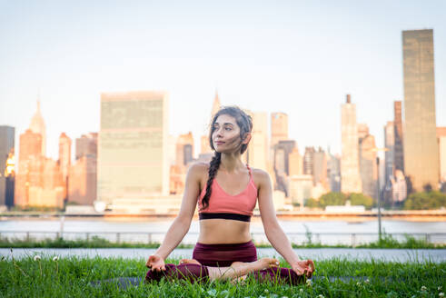 Schöne sportliche Frau macht Yoga-Meditation in einem Park - Mädchen entspannt mit heiterem Ausdruck im Freien - DMDF03297