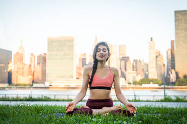 Beautiful sportive woman doing yoga meditation in a park - Girl relaxing with serene expression outdoors - DMDF03298