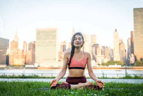 Schöne sportliche Frau macht Yoga-Meditation in einem Park - Mädchen entspannt mit heiterem Ausdruck im Freien - DMDF03298