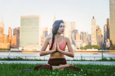 Beautiful sportive woman doing yoga meditation in a park - Girl relaxing with serene expression outdoors - DMDF03299