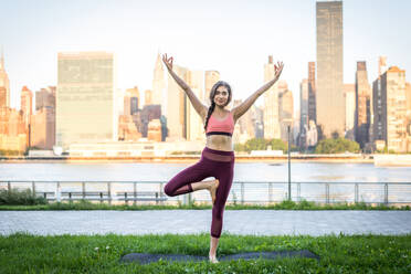 Schöne sportliche Frau macht Yoga-Meditation in einem Park - Mädchen entspannt mit heiterem Ausdruck im Freien - DMDF03304