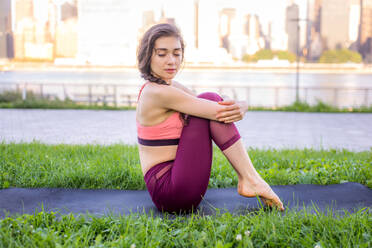 Beautiful sportive woman doing yoga meditation in a park - Girl relaxing with serene expression outdoors - DMDF03310