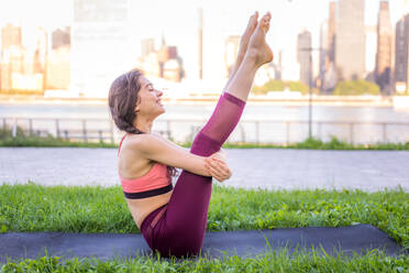 Beautiful sportive woman doing yoga meditation in a park - Girl relaxing with serene expression outdoors - DMDF03311