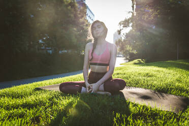 Schöne sportliche Frau macht Yoga-Meditation in einem Park - Mädchen entspannt mit heiterem Ausdruck im Freien - DMDF03315