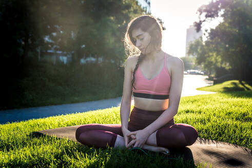 Schöne sportliche Frau macht Yoga-Meditation in einem Park - Mädchen entspannt mit heiterem Ausdruck im Freien - DMDF03316