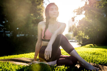 Beautiful sportive woman doing yoga meditation in a park - Girl relaxing with serene expression outdoors - DMDF03317