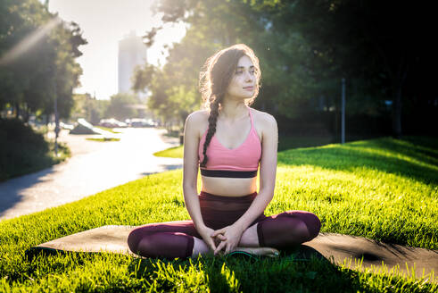 Schöne sportliche Frau macht Yoga-Meditation in einem Park - Mädchen entspannt mit heiterem Ausdruck im Freien - DMDF03318