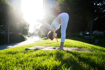 Beautiful sportive woman doing yoga meditation in a park - Girl relaxing with serene expression outdoors - DMDF03320